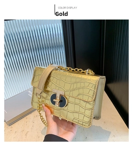 Detail of gold faux crocodile texture and metallic T-lock on the chain square bag