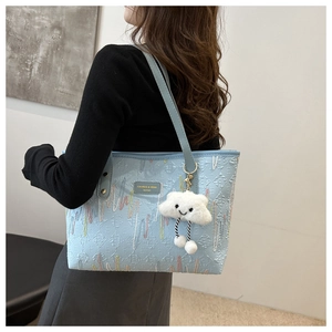 Detail of light blue tote bag with colorful embroidery and white plush cloud pendant