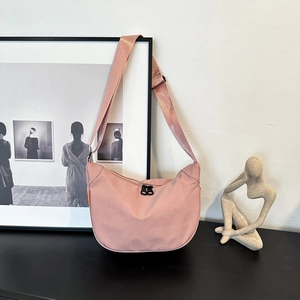 Pink minimalist waterproof oxford crescent bag with adjustable strap on a modern tabletop