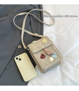 Detailed size comparison of the beige mini heart crossbody bag with a smartphone