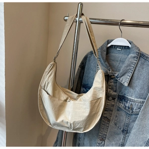 Détail du sac croissant en nylon beige minimaliste avec large bandoulière et grand compartiment