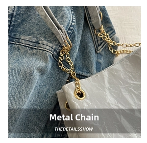Detailed view of the gold chain strap and textured gray fabric on this stylish shoulder bag