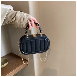 Detail of vertical quilted black crossbody box bag with gold-tone hardware and twist handle