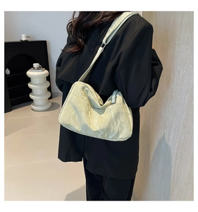 Detail of light green pleated shoulder bag with elegant pearl chain on fashion model