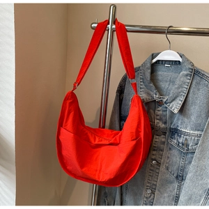 Vue détaillée d'un sac demi-lune rouge vif assorti à une veste en jean bleu classique