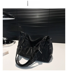 Close-up of black marble-textured tote bag showing the wide strap and silver buckle