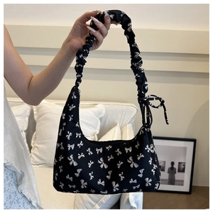 Detail of black underarm bag with white bow prints and ruched handle for women