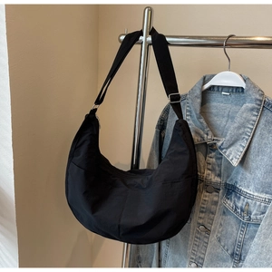Détail du sac croissant en nylon noir avec large bandoulière et boucle en métal argenté