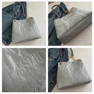 Close-up of silver pleated tote bag with FASHION embossing and chain strap details