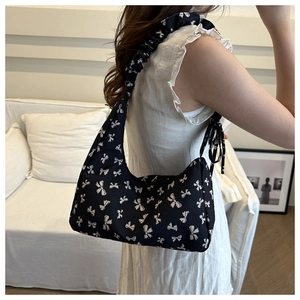Detail of crossbody bag with black bow print and unique ruched shoulder strap design
