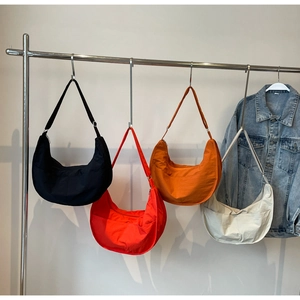 Détail de sacs bandoulière croissants en nylon en noir, rouge, orange et beige