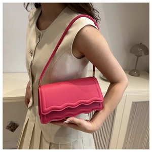 Detailansicht der pinkfarbenen Wellenkanten-Umhängetasche mit Schnalle und Riemen am Model