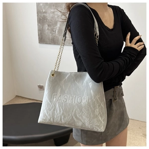 Close-up of pleated texture and FASHION embossing on minimalist chain tote bag