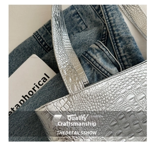 Macro shot of silver crocodile embossed texture on a stylish tote bag with metallic finish