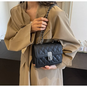 Close-up of black quilted shoulder bag with silver turn-lock and chain strap detail