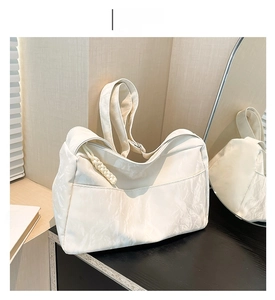 Detail of off-white soft leather shoulder bag with unique pleated texture and woven zipper pull