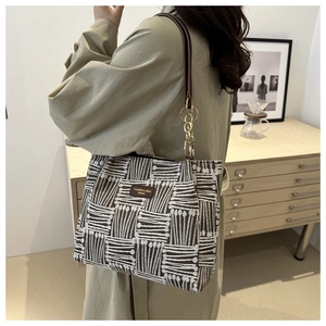 Detail of woven tote bag with black and white stripes and brown leather brand logo