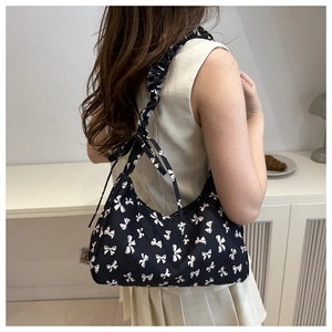 Detail of black crescent shoulder bag with white bow prints and ruched strap