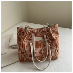 Detail of orange checkered woven tote bag with white leather straps and gold chain link