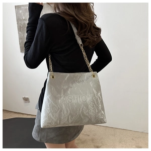 Detail of grey wrinkled tote bag with embossed lettering and gold chain strap