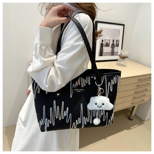 Detail of black tote bag featuring colorful zigzag embroidery and cloud charm on model