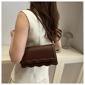Detail view of coffee brown shoulder bag with unique wavy pleated flap design