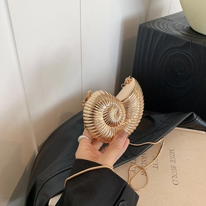 Golden nautilus shell crossbody bag with spiral metallic texture and fine chain strap