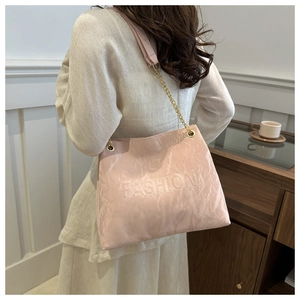 Detail of pink tote bag with embossed fashion text and elegant gold chain strap