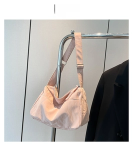 Pink crescent nylon shoulder bag with adjustable strap and textured pleated surface