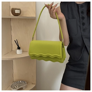 Détail du sac en cuir vert avec rabat à bord ondulé et finitions en métal doré brillant