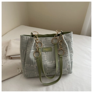 Detail of grey-green geometric fabric tote with gold chain and branded leather patch
