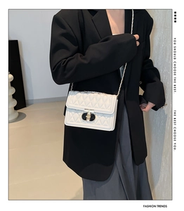 Détail du sac bandoulière blanc matelassé avec fermoir métal et chaîne sur un mannequin