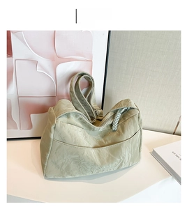 Detail view of the soft green tote bag showing wrinkled leather texture and woven zipper pull