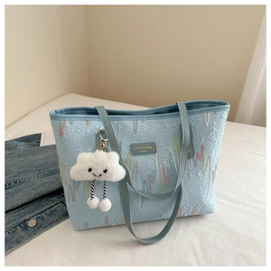 Detail of light blue tote bag with colorful wave embroidery and white cloud charm