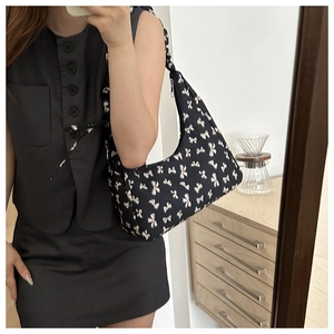Detail of hobo shoulder bag featuring white bow patterns and smooth top zipper closure