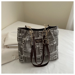 Close-up of brown striped tote bag with gold chain link and woven texture details