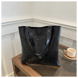 Detailed macro shot of glossy black crocodile embossed texture on a large tote bag