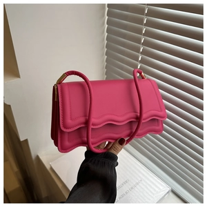 Detail der fuchsiafarbenen Ledertasche mit Wellenrand und Akkordeon-Seitendesign