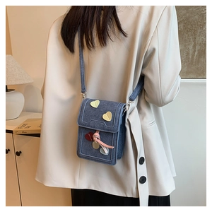 Detail of blue denim crossbody phone bag with colorful heart-shaped metal ornaments