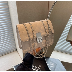 Detail of cream quilted crossbody bag featuring silver turn-lock and chain strap textures