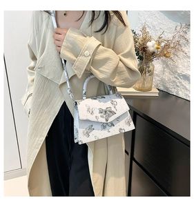 Detail of silver bow clasp and butterfly print on white faux leather handbag