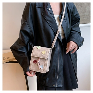 Side view of beige crossbody phone bag with colorful hearts worn by a model