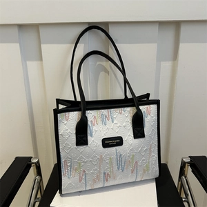 White embroidered tote bag with colorful wave patterns and black leather handles