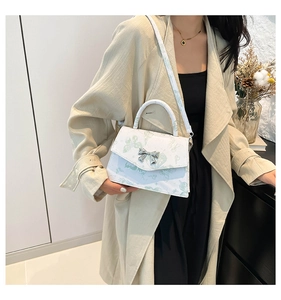 Sac à main blanc avec motifs papillons et fermoir nœud porté par un mannequin en mode