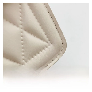 Gros plan sur la texture en cuir matelassé beige et les coutures d'un petit sac à main