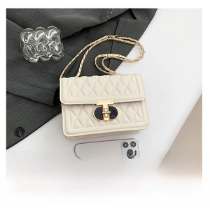 Détail du sac matelassé blanc avec bandoulière dorée et référence de taille avec un mobile