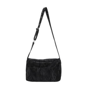 Minimalist black tote bag with unique pleated texture and adjustable strap on white background
