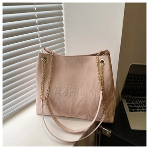 Detail of light pink tote bag with FASHION embossed texture and gold chain strap