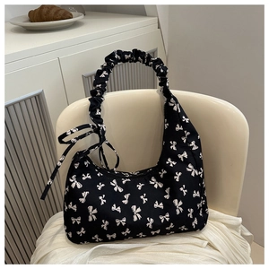 Detail of black baguette bag with white bow prints on a French style chair