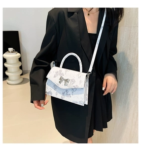 Vue détaillée du sac bandoulière blanc à motif papillon et boucle nœud argenté